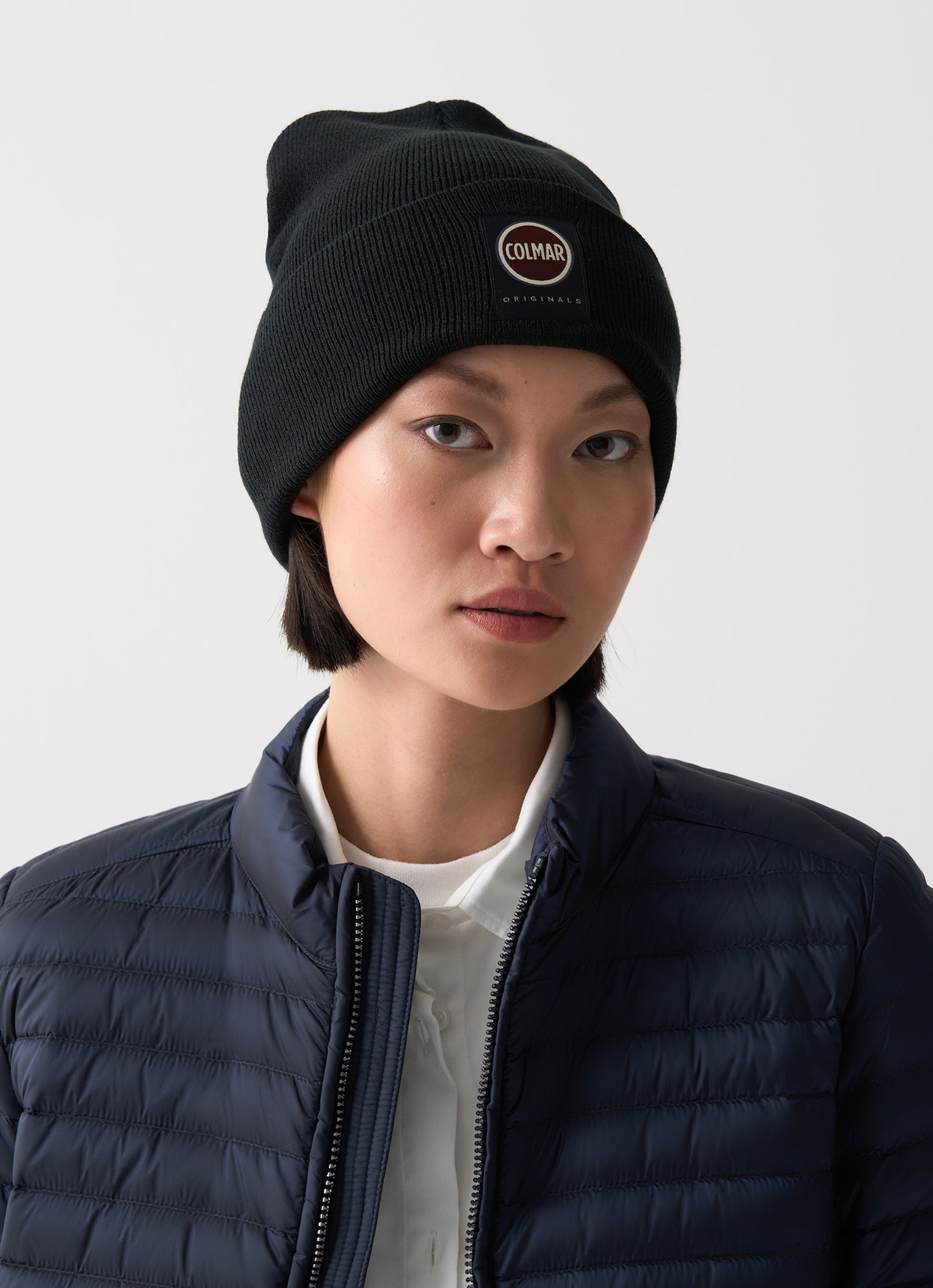 Cappello unisex Colmar in maglia nera con risvolto e logo frontale indossato donna
